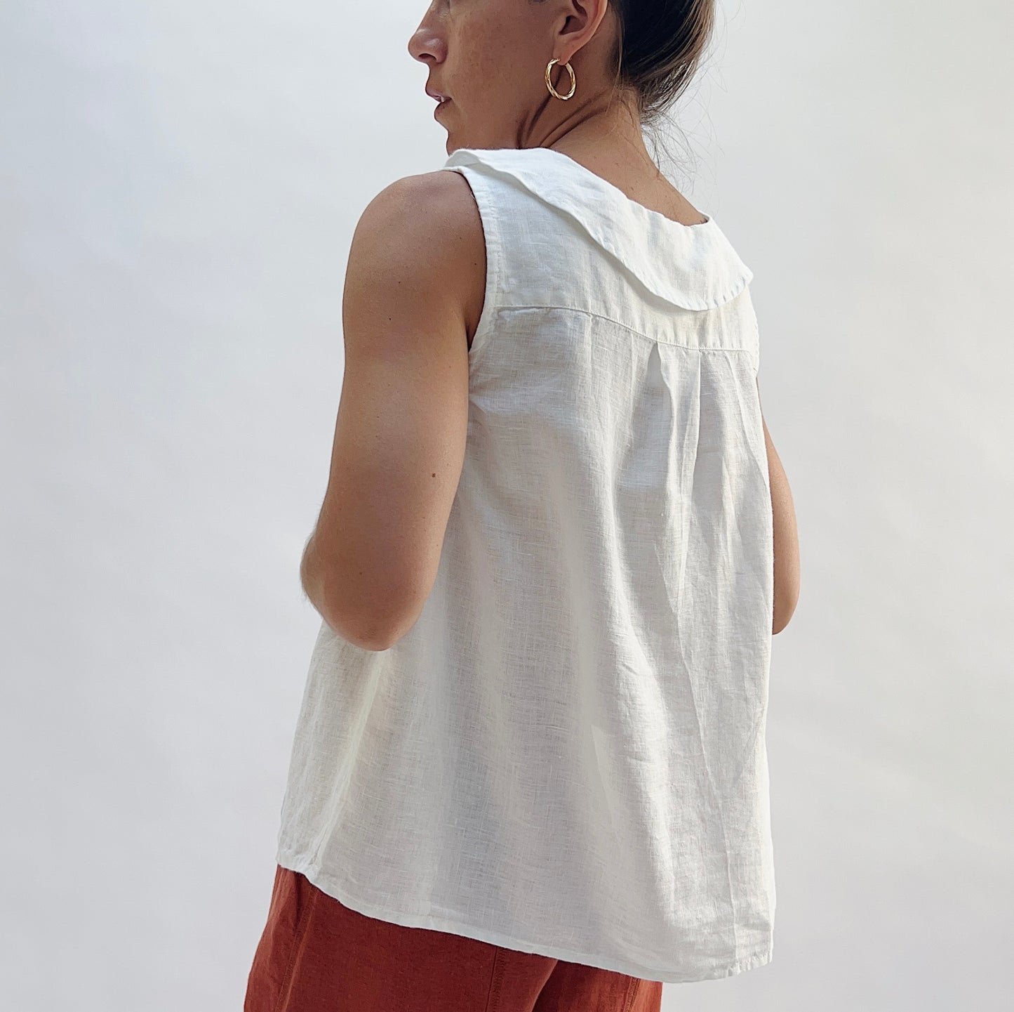 Back view of the Sailor Tank in White by Yuvita, showing the sailor collar, pleated back yoke, and relaxed linen drape in white, styled with terracotta linen wide-leg pants