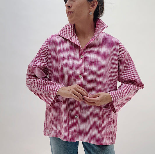 Pink Gingham Button Front Blouse — front view showing pink-and-white mini gingham check, spread collar, three shell buttons, two front patch pockets, and long sleeves, worn with blue jeans on a white background