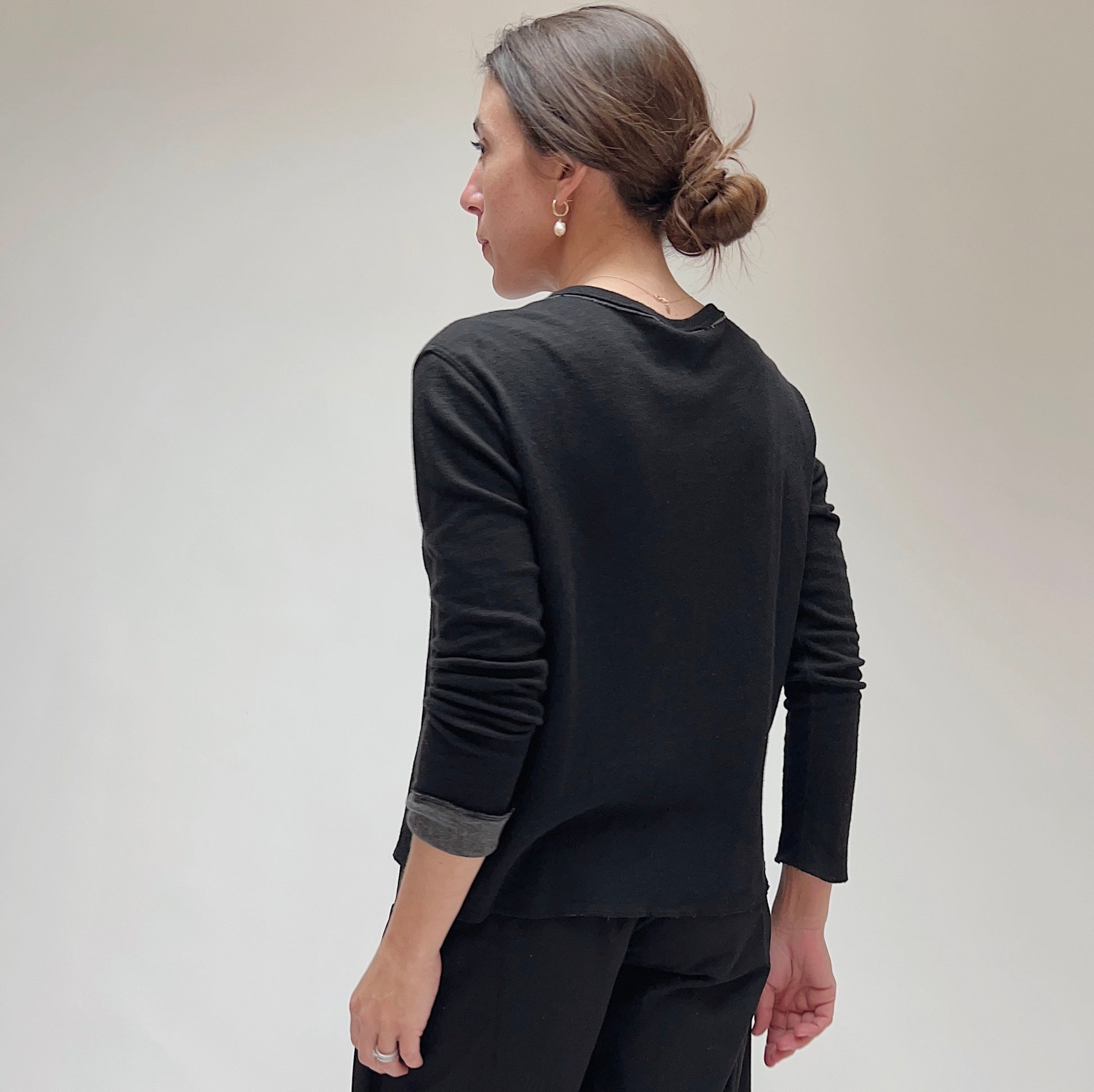 Back view of the black snap front cardigan showing clean back panel, contrast cuff detail, and relaxed fit