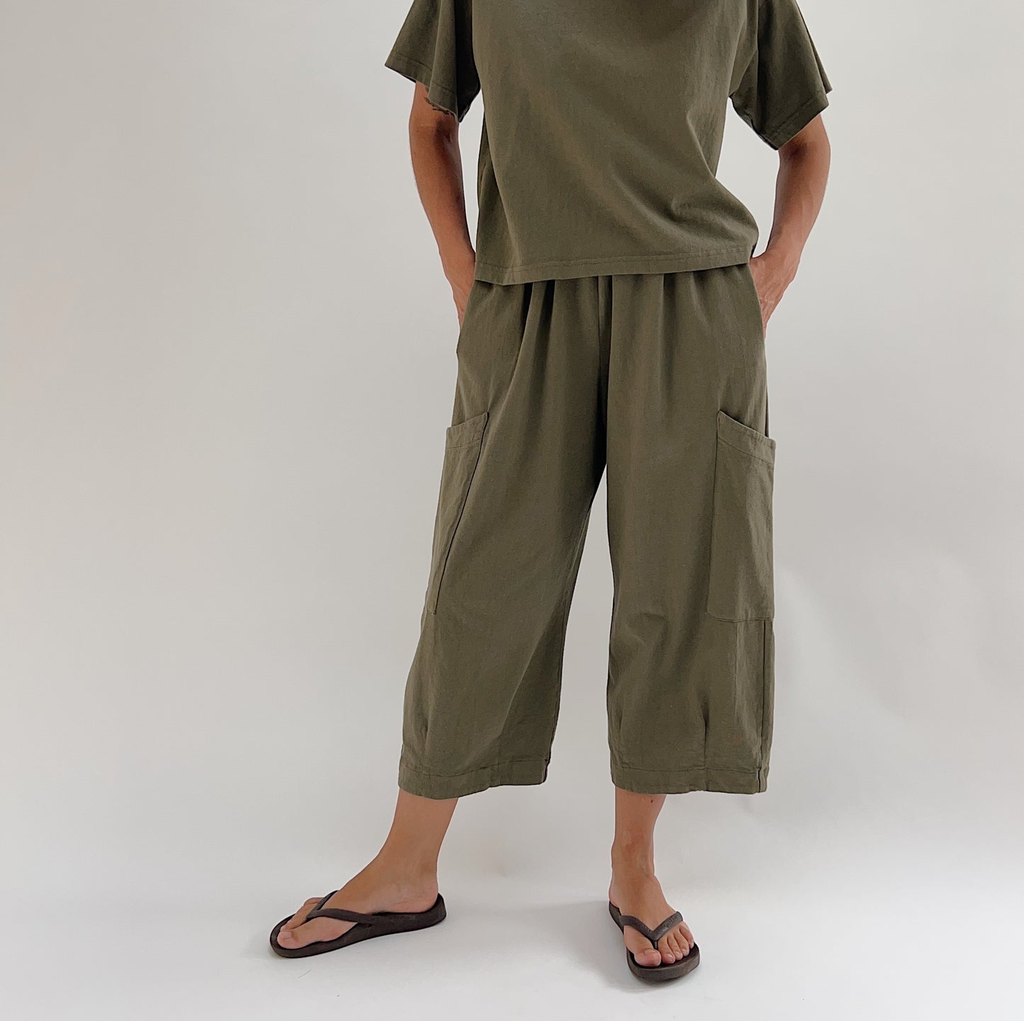 Front view of model wearing Bryn Walker jasper cotton Pasha pant, showing wide-leg silhouette, large patch pockets, elastic waist, and cropped capri length with banded hem