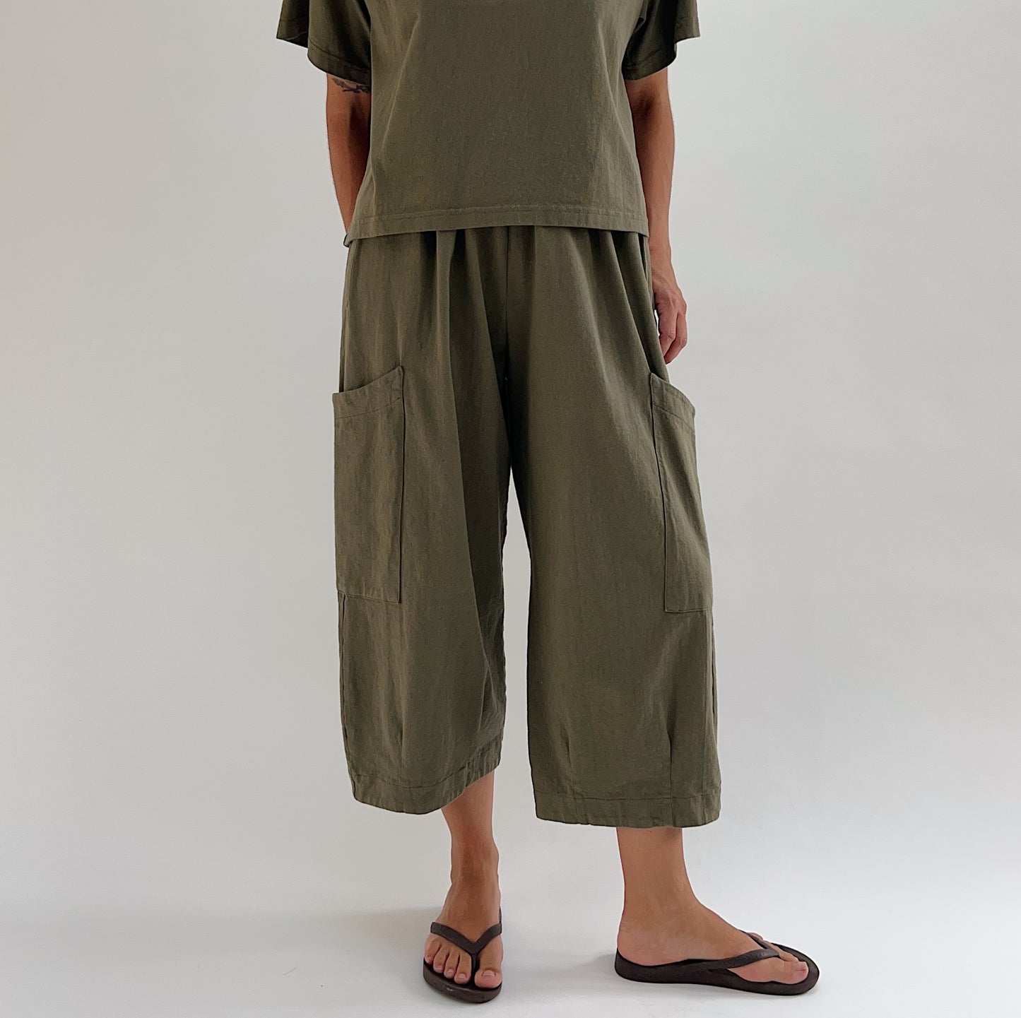Full front view of model wearing Bryn Walker jasper Pasha pant, showing both large patch pockets, relaxed wide-leg fit, elastic waist, and banded capri hem