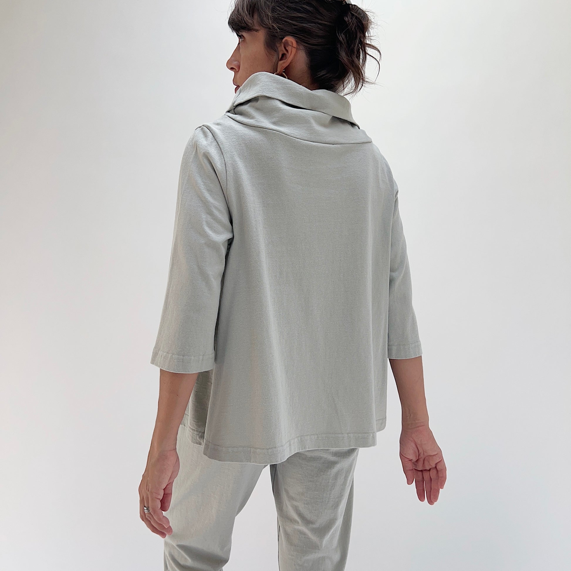 Back view of model wearing Bryn Walker orlaya 3/4 sleeve Etta top, showing draped cowl at back neckline, boxy A-line silhouette, 3/4 sleeves, and banded hem