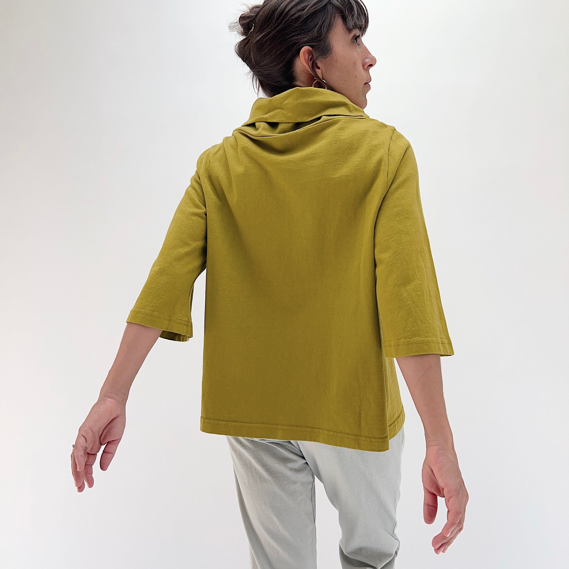 Back view of model wearing Pacific Cotton chartreuse 3/4 sleeve Etta top, showing draped cowl at back neckline, boxy A-line silhouette, 3/4 sleeves, and banded hem