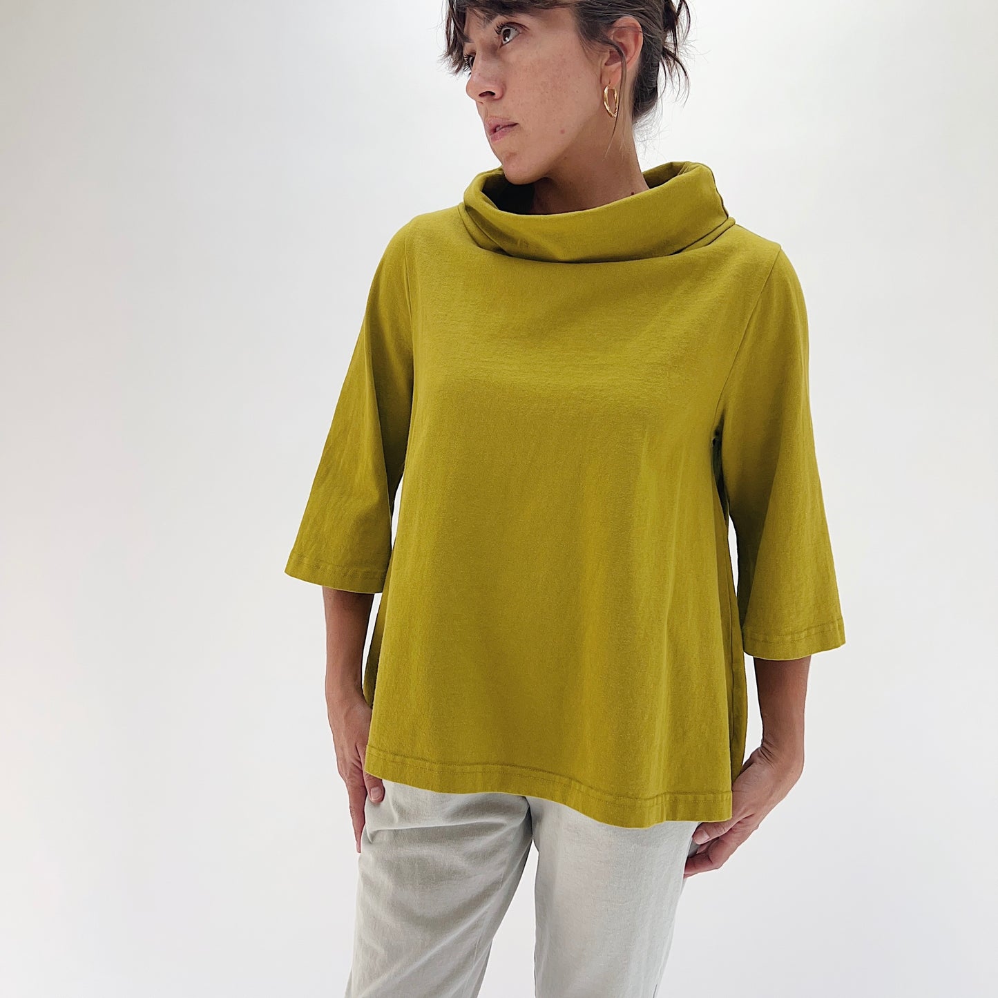 Full front view of model wearing Pacific Cotton chartreuse 3/4 sleeve Etta top, showing draped cowl neckline, wide 3/4 sleeves, boxy A-line fit, and banded hem
