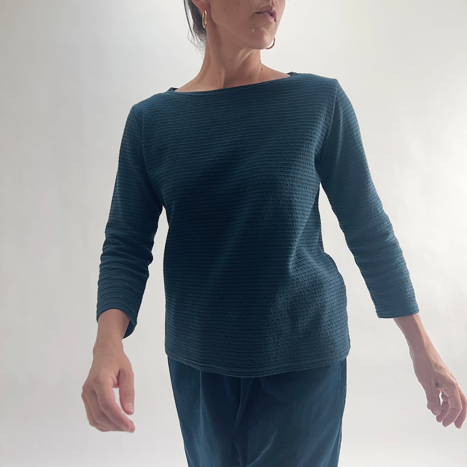 Front view of model wearing a deep teal tonal textured stripe boatneck tee with 3/4 sleeves and a relaxed fit, styled with matching teal wide-leg pants against a white background.

