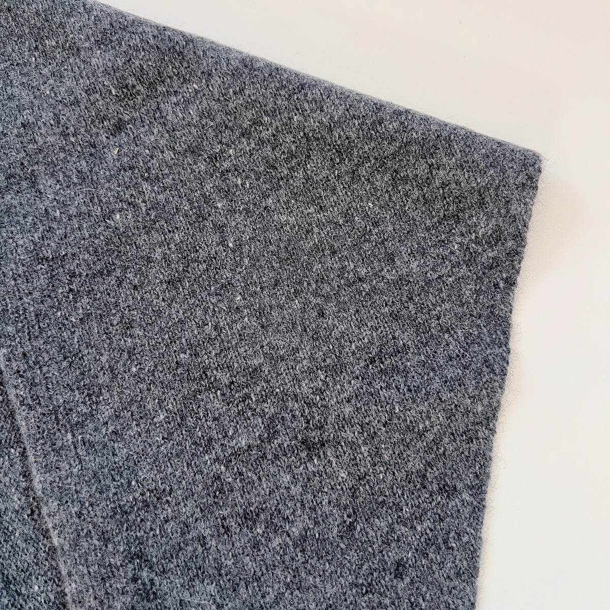 Close-up of the Charcoal merino wool scarf showing its heathered knit texture and finished edge.
