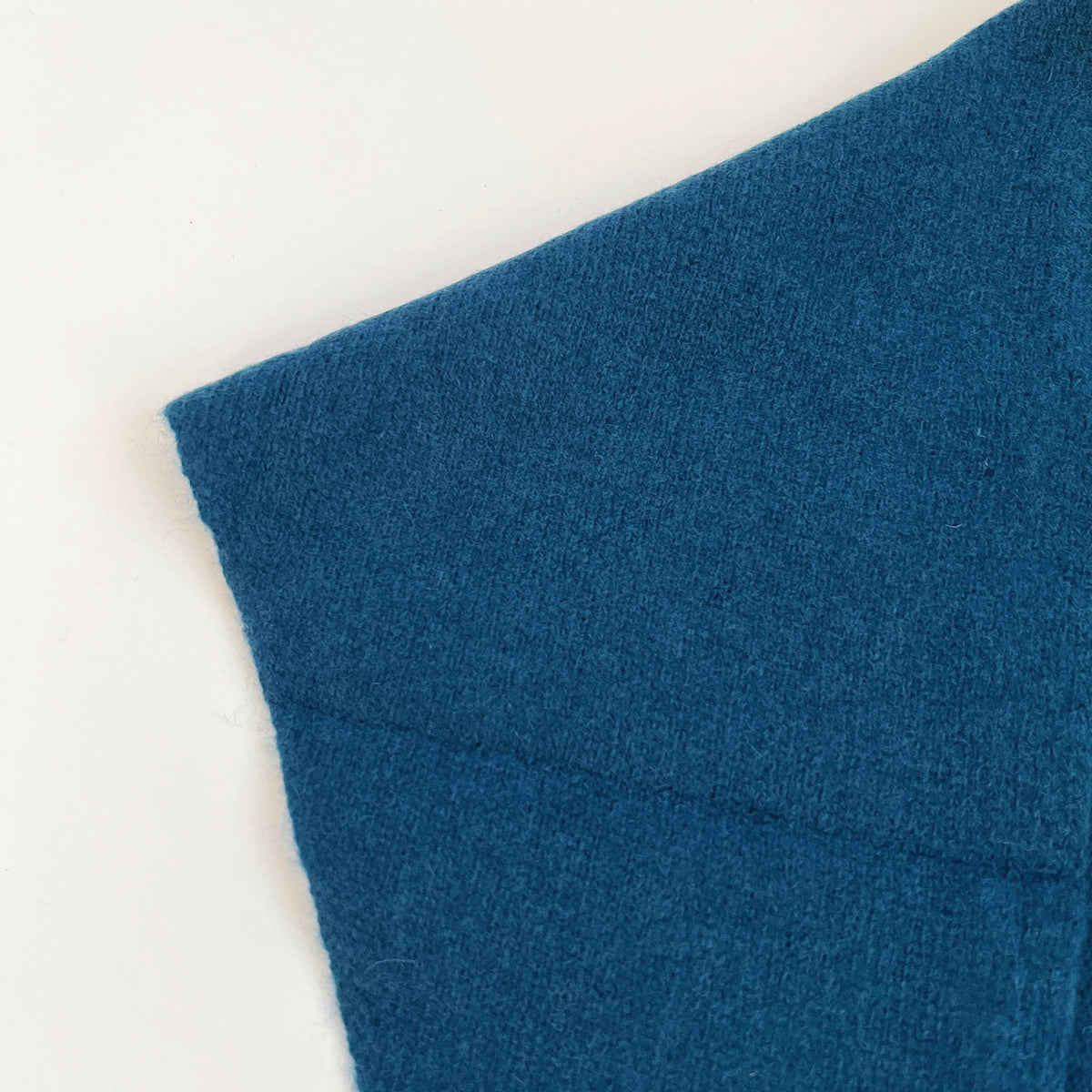 Close-up of the Ocean blue merino wool scarf showing its knit texture and finished edge.
