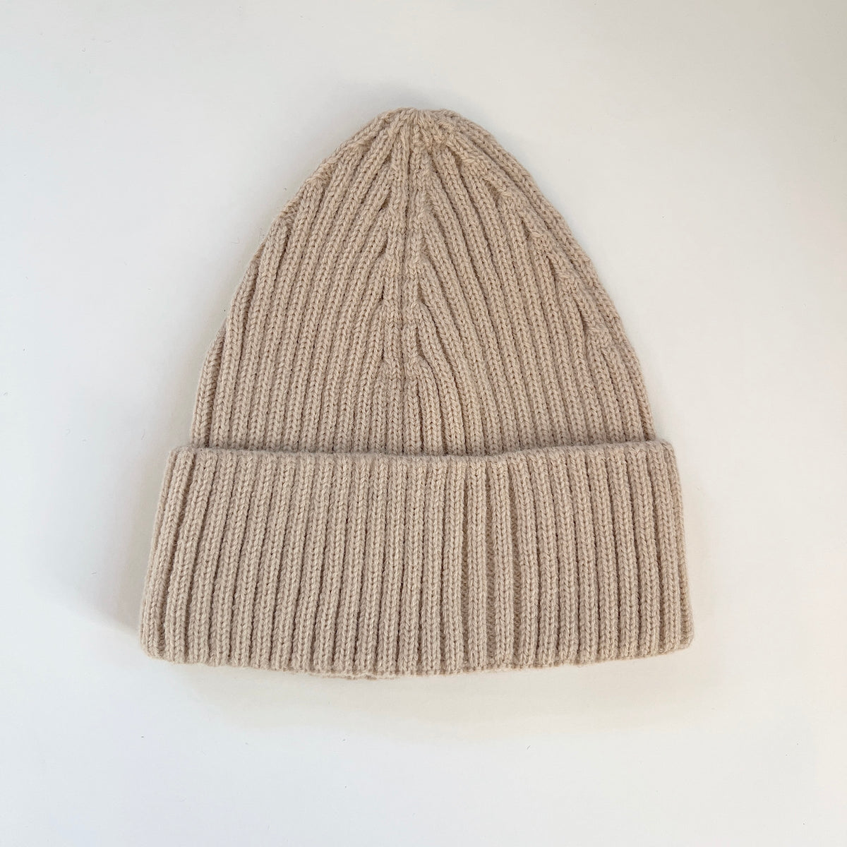 Oatmeal ribbed lambswool beanie laid flat with a wide fold-over cuff.
