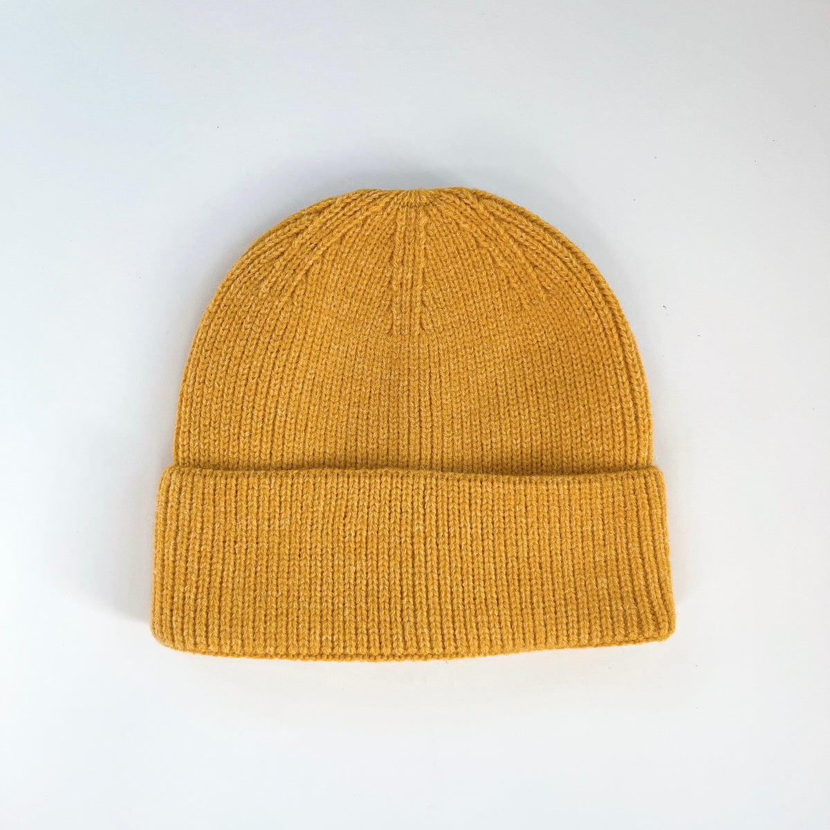 Lemon yellow lambswool beanie laid flat with a rounded knit crown and ribbed fold-over cuff.
