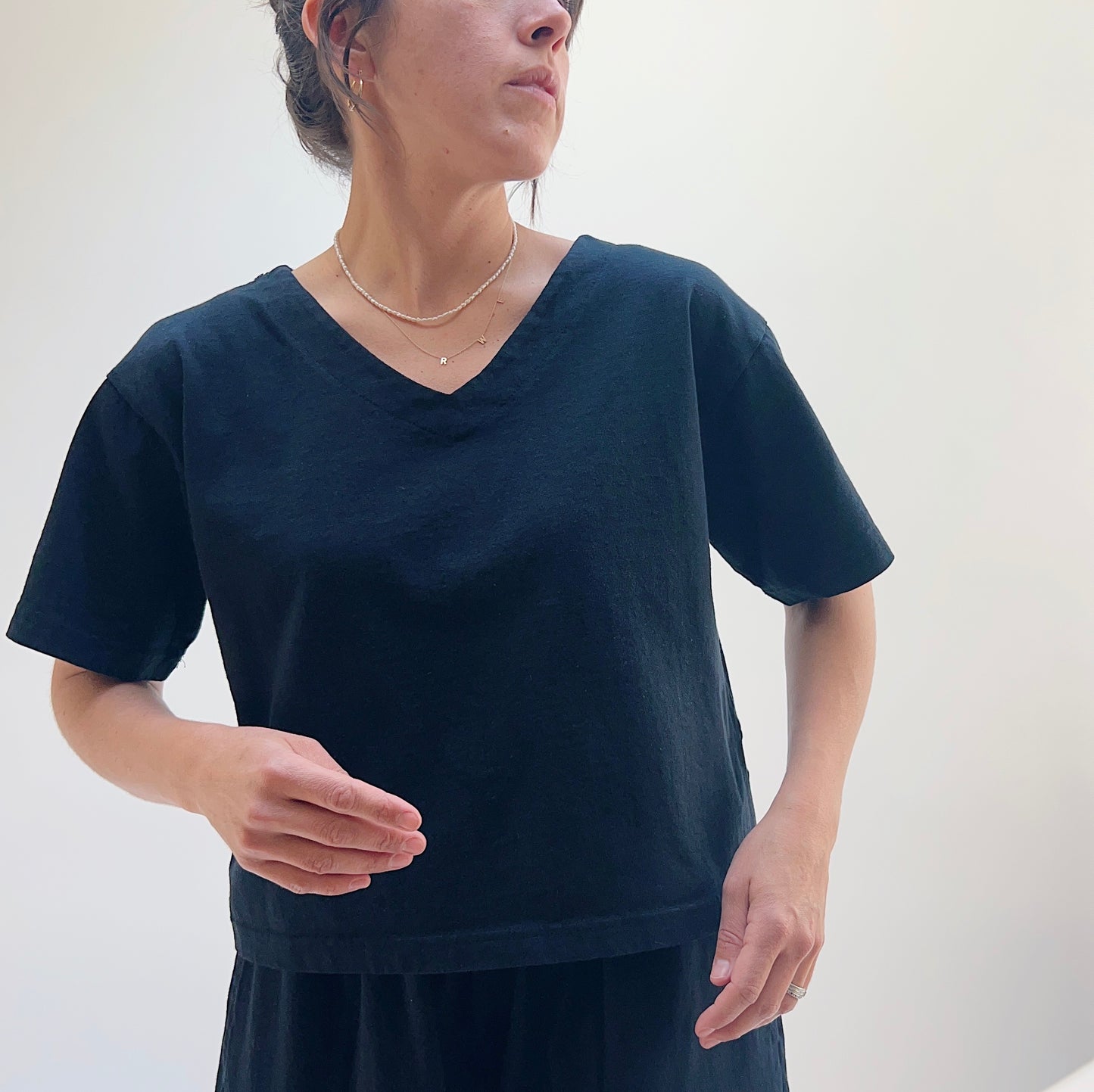 A person wearing a black crop V-neck t-shirt 