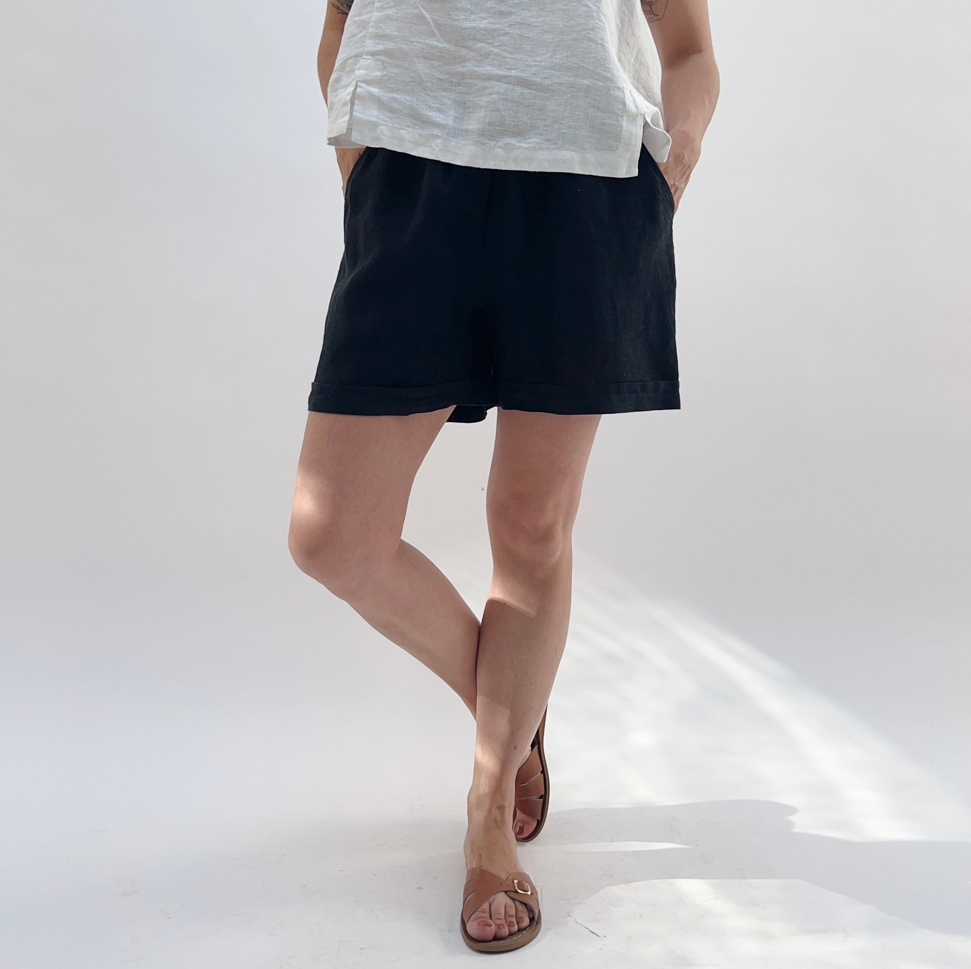 Person wearing black shorts and a white top on a white background