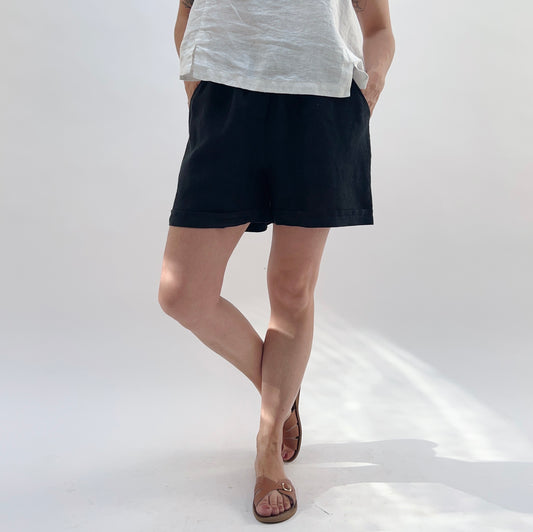 Person wearing black shorts and a white top on a white background