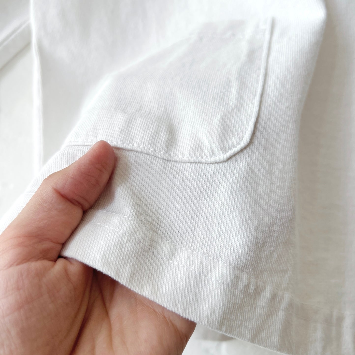 Close-up of a hand holding a white fabric pocket with a blurred background