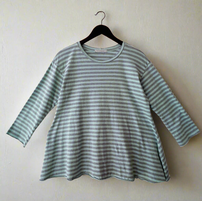 Green and white striped shirt on a hanger against a white wall