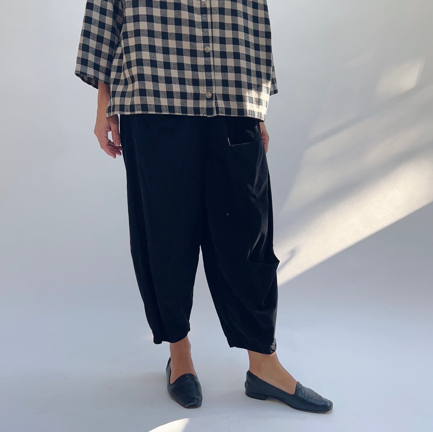 Back view of black corduroy three pocket pant showing relaxed silhouette, tapered crop hem, and back pocket detail
