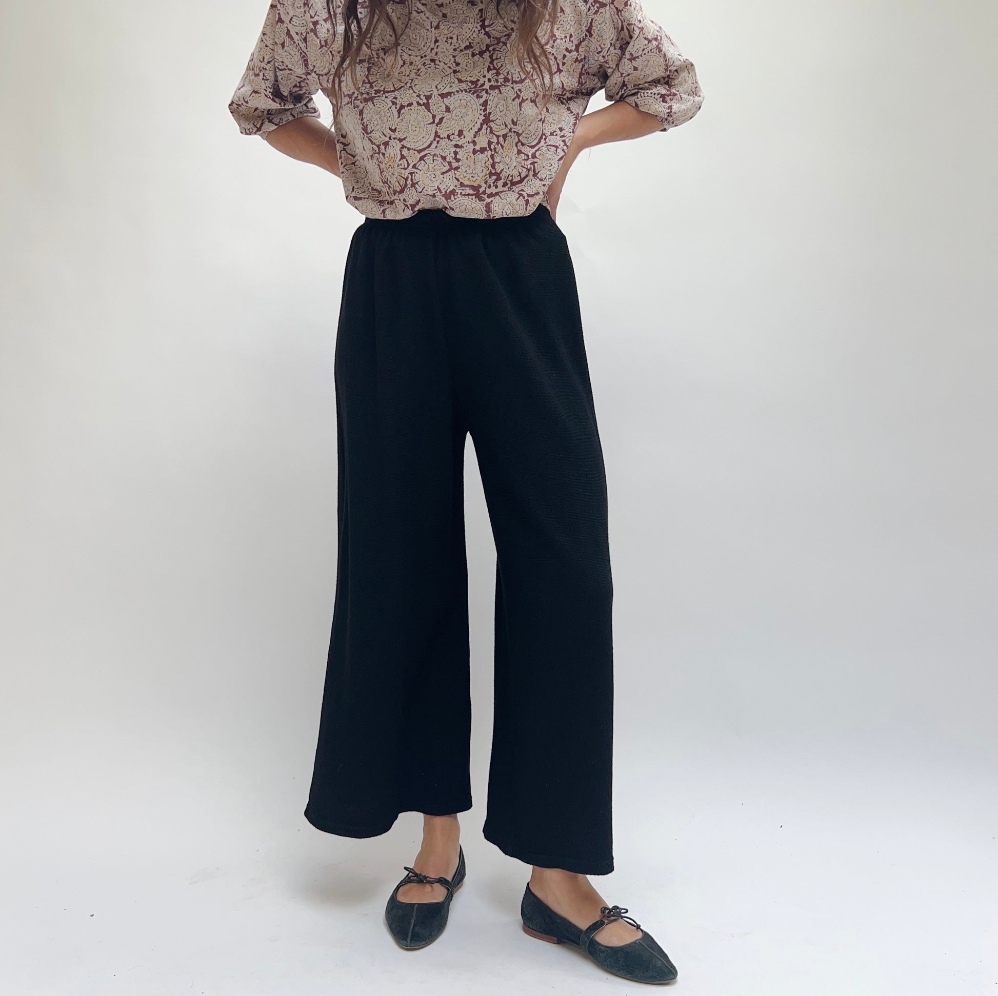 Cut Loose Marled Knit Crop Pant in Black, front view, wide-leg silhouette with elastic waistband, worn with a floral blouse and black ballet flats

