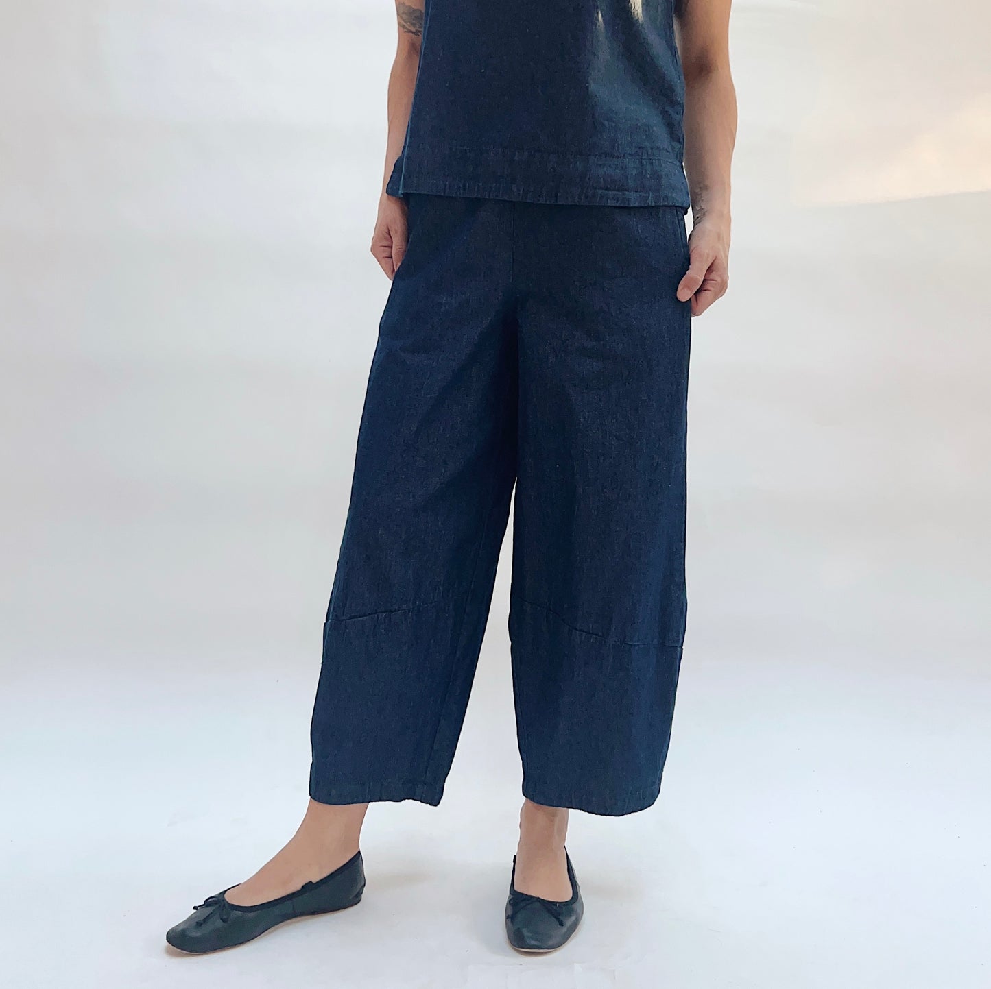 Person wearing navy blue pants and top on a white background