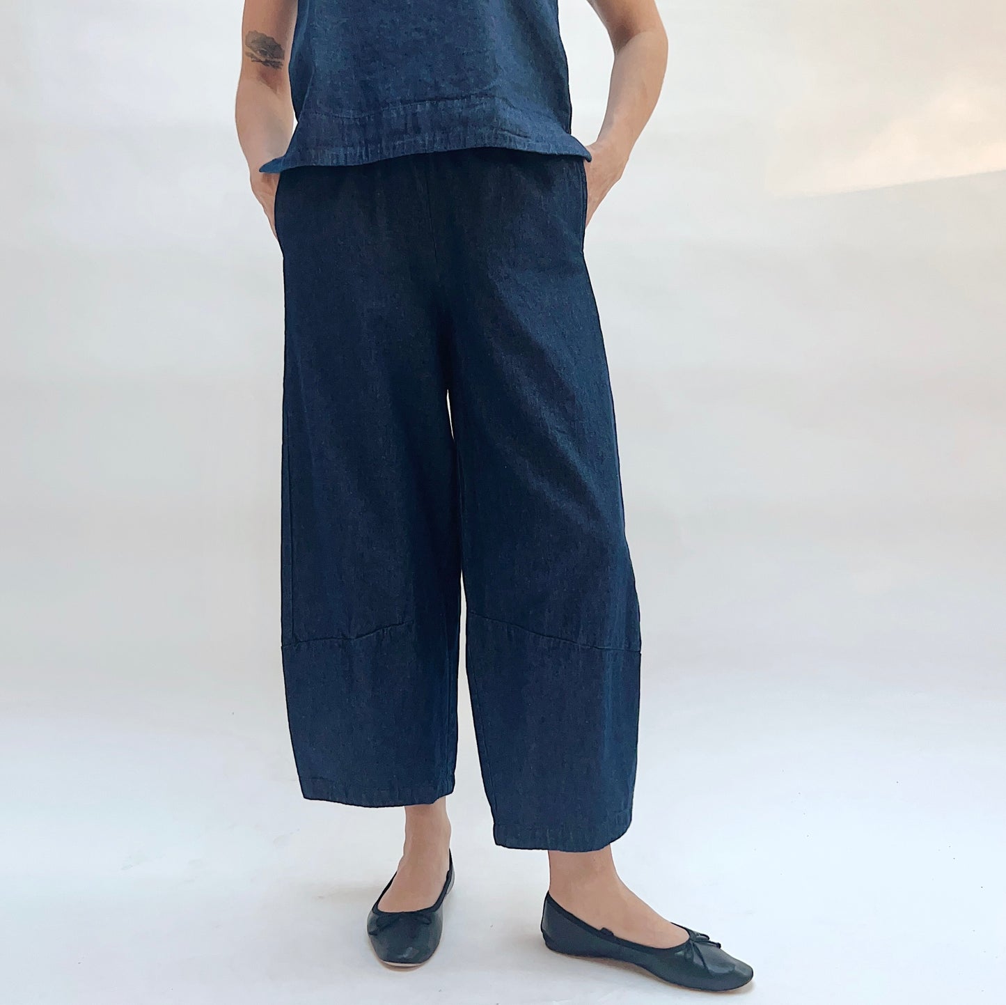 Person wearing a sleeveless denim top and wide-leg denim pants on a white background