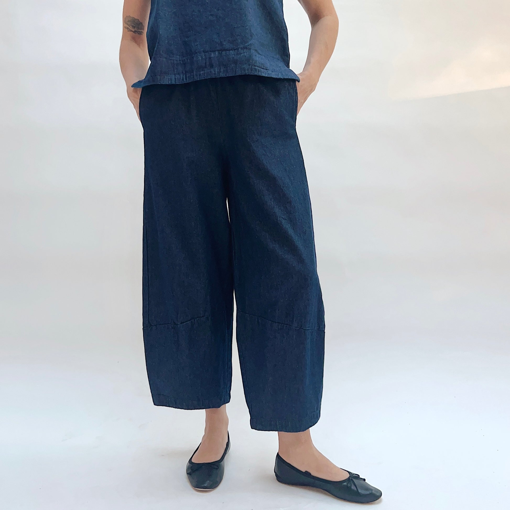 Person wearing a sleeveless denim top and wide-leg denim pants on a white background