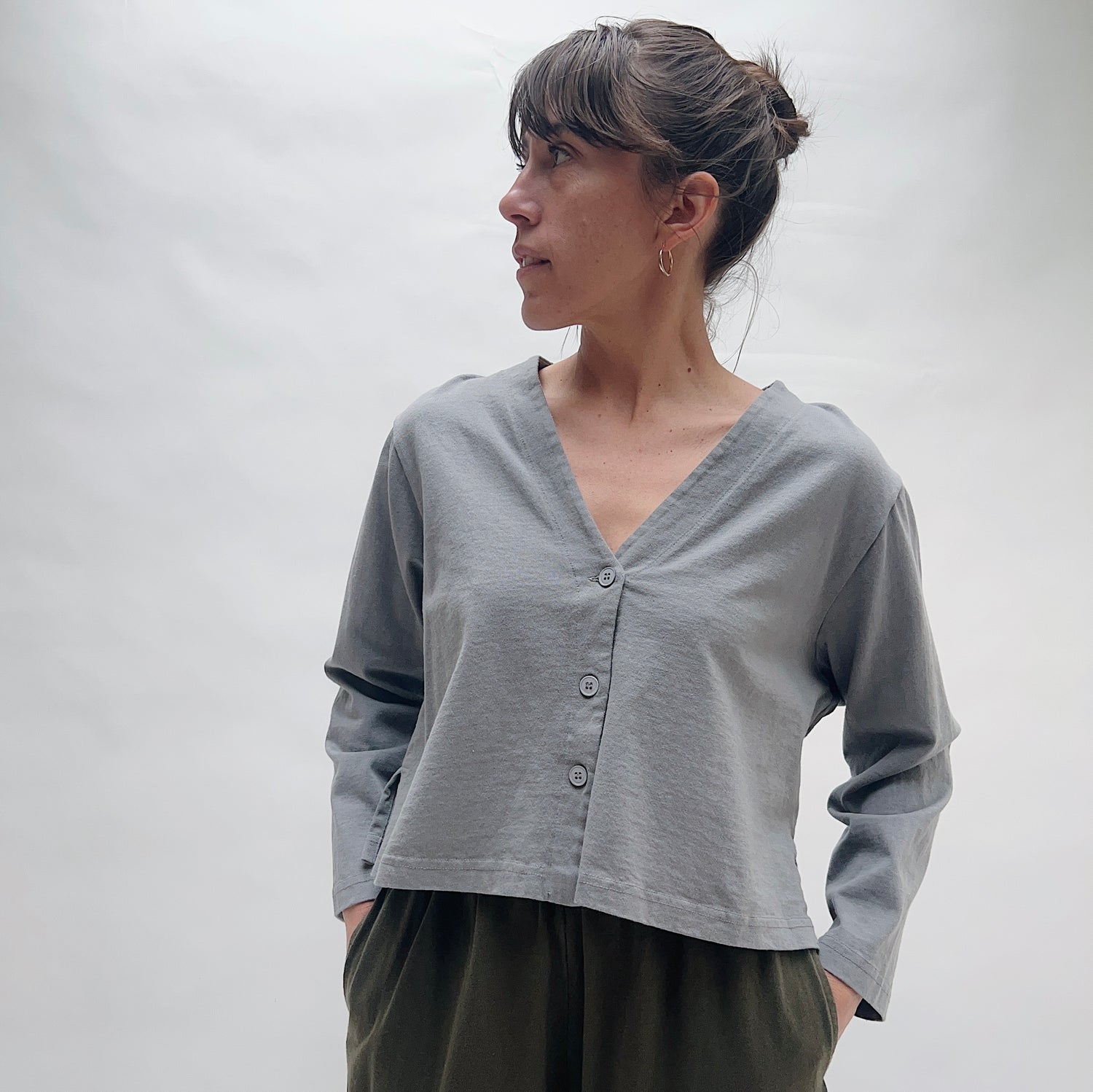 Woman wearing a gray long-sleeve cardigan with a v-neckline against a white background