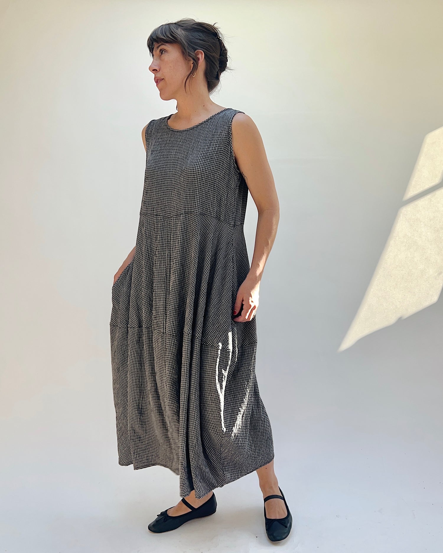 Woman wearing a sleeveless, patterned dress against a white background
