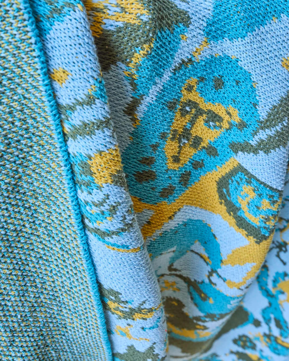 Close-up of the French Cirque Aqua blanket’s yellow lion, aqua and pale blue knit, and textured reverse.
