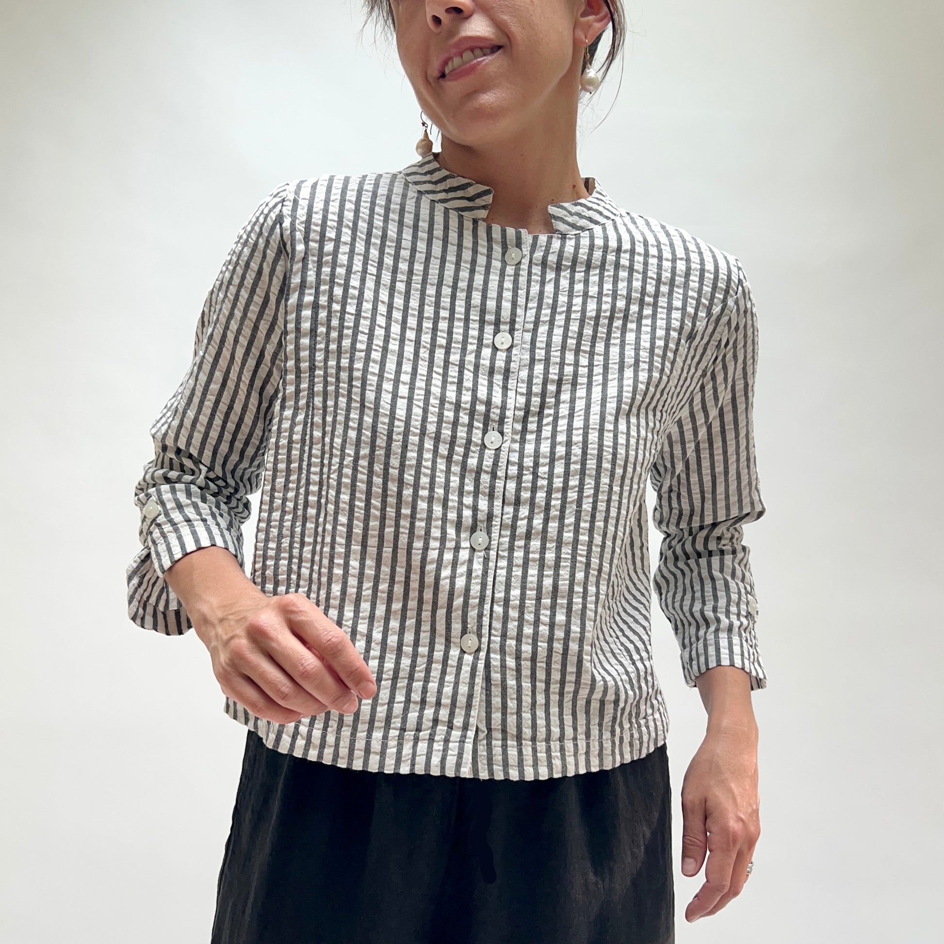 Person wearing a black and white striped shirt against a plain background