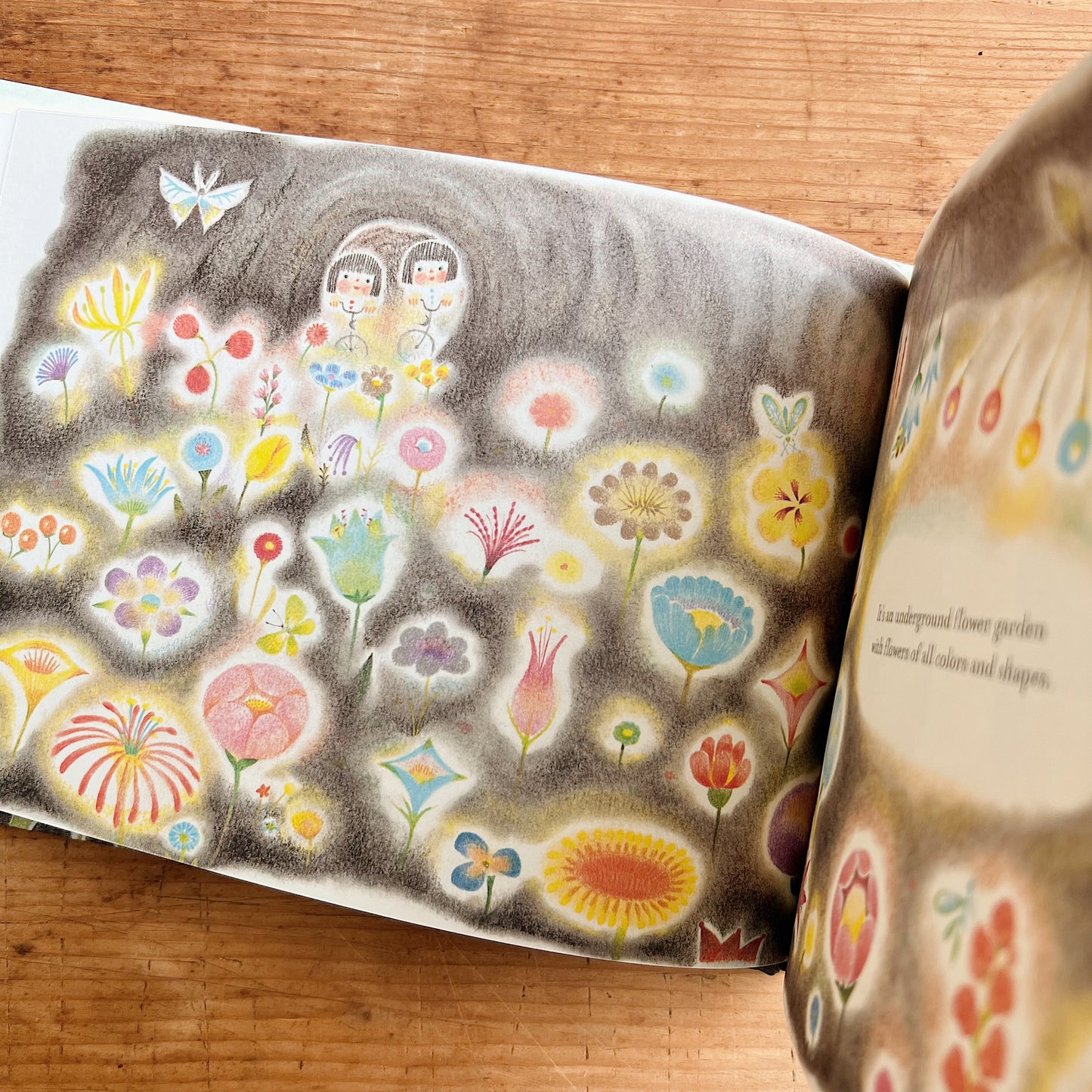 A close-up of the inside of the book opened to a page showing two girls riding bikes through a field of flowers.