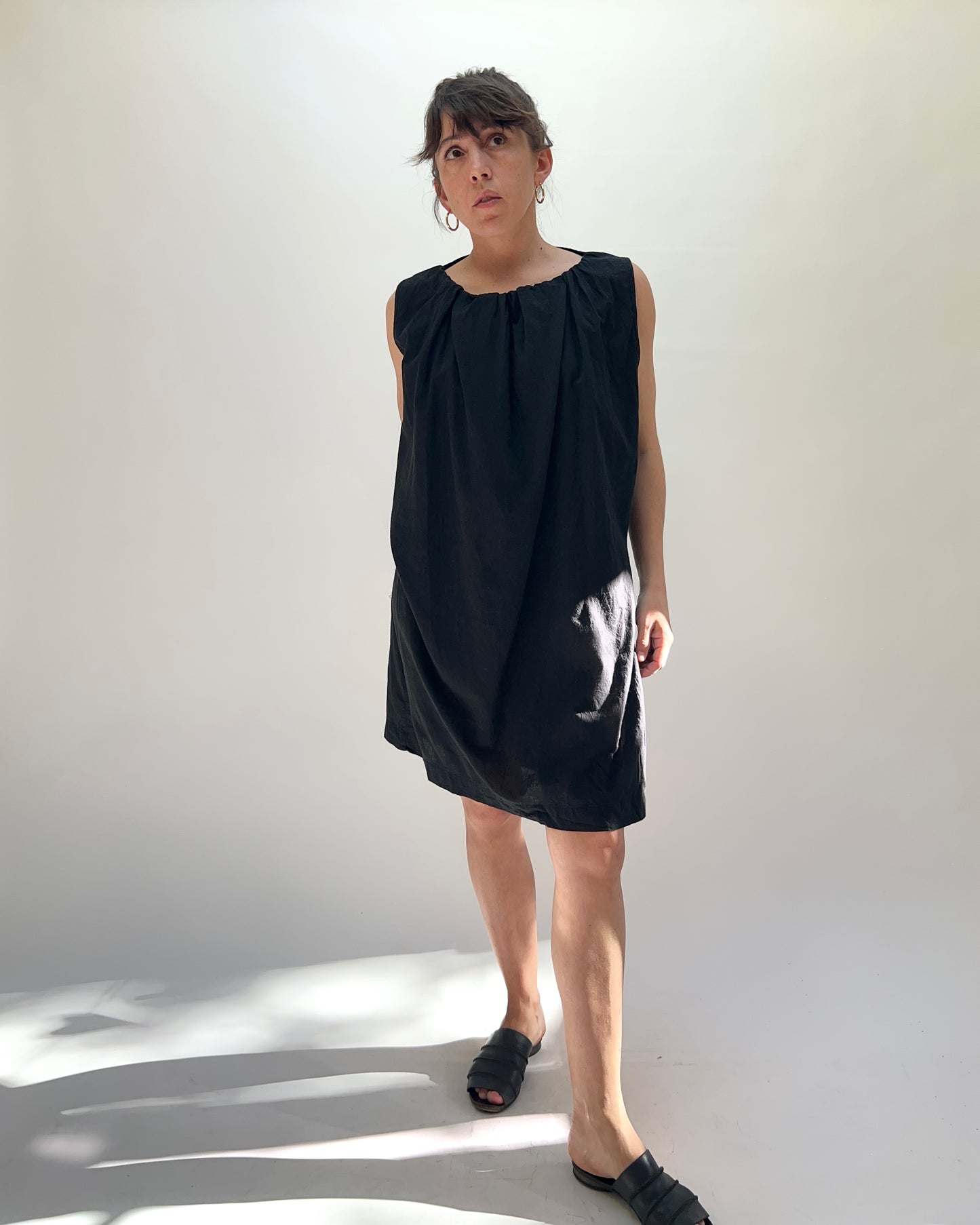 Woman wearing a black sleeveless dress against a white background