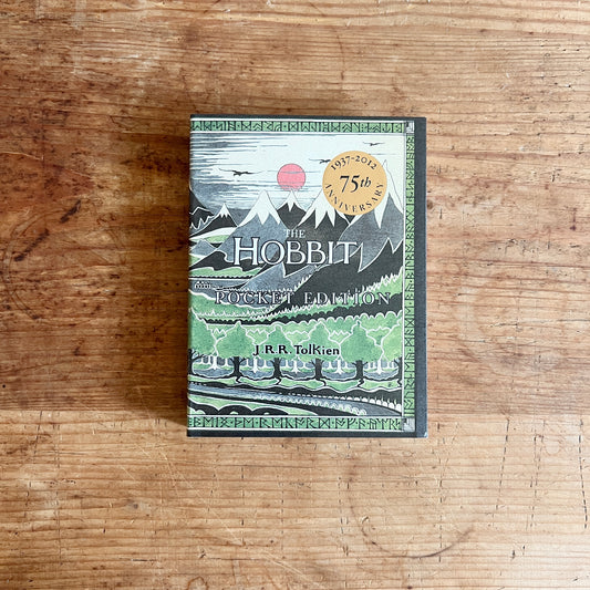 Cover of The Hobbit: Pocket Edition by J.R.R. Tolkien, showing mountains, trees, and a red sun.
