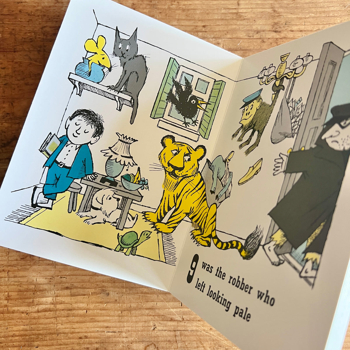 Open pages of One Was Johnny showing Johnny surrounded by animal visitors as a robber enters, with the rhyme “9 was the robber who left looking pale.”
