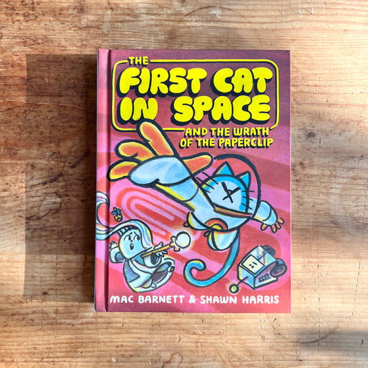 Cover of The First Cat in Space and the Wrath of the Paperclip, showing a blue cat in a spacesuit against a pink background.

