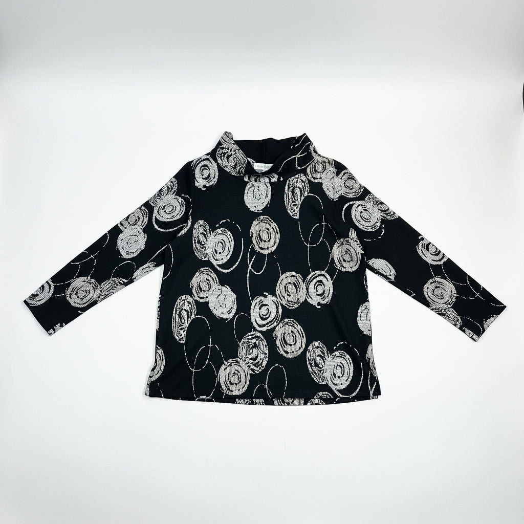 Christopher Calvin Knit Mock Neck Top in Circle Print on hanger, front view showing white crosshatch-textured concentric circle woven jacquard motifs on black, folded mock neck collar, long sleeves, and relaxed A-line silhouette
