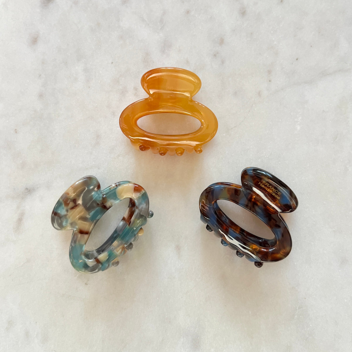 Three tortoiseshell patterned hair clips on a light gray background