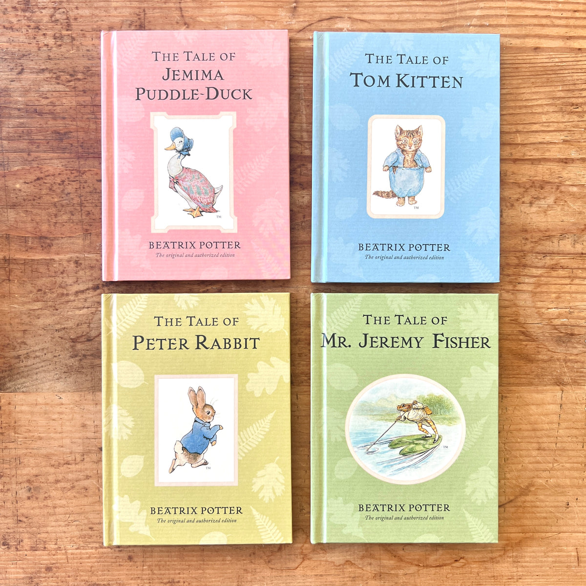 Four Beatrix Potter books on a wooden surface