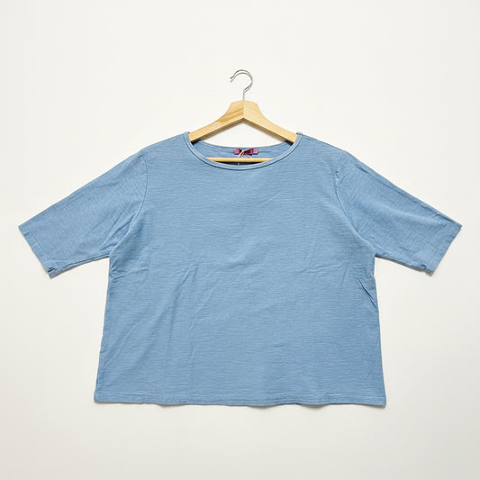 Blue t-shirt on a wooden hanger against a white background