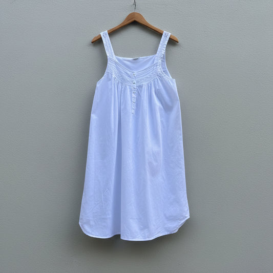 White dress on a wooden hanger against a gray wall