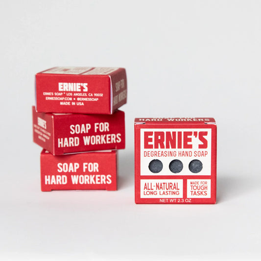 Three red boxes of Ernie's Hard Workers soap bars arranged on a light gray studio background, with one box open to show the dark soap bars inside and another box beside it labeled 'Degreasing Hand Soap'.