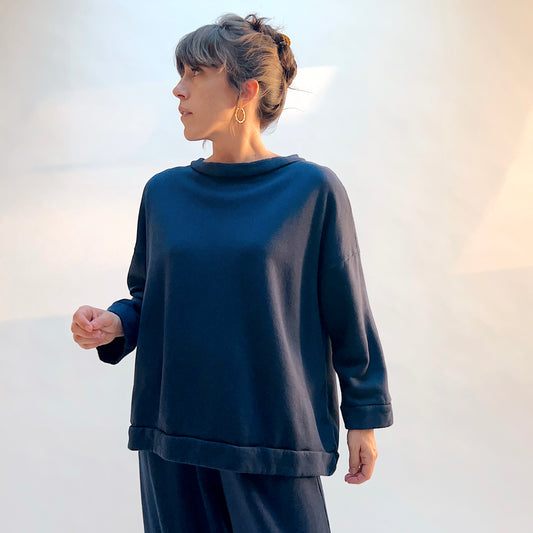 Front view of Bryn Walker Alden Fleece Sweatshirt in Nova, a deep navy blue, showing the draped neckline, dropped shoulders, and banded hem.
