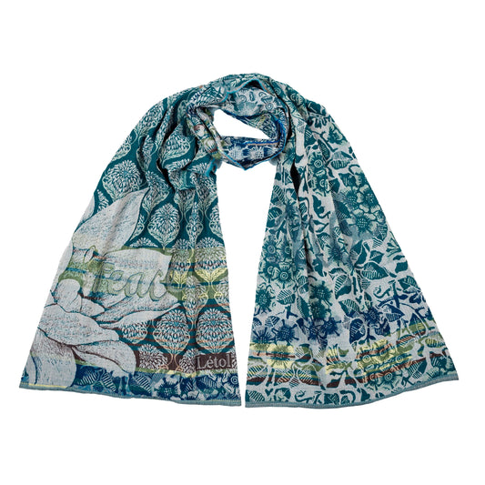 Létol Louise Scarf in Cedar Teal, looped and laid flat against a white background showing both sides simultaneously — one side featuring a bold deep teal ogee lattice filled with Mughal tree-of-life motifs and a large botanical magnolia in the lower corner with the woven Létol signature, the other showing a dense all-over teal floral and bird print on a pale ground with sunflower, thistle, and fauna motifs,
