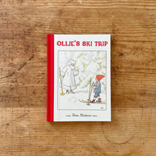 Load image into Gallery viewer, Front cover of Elsa Beskow&#39;s mini hardcover book, Ollie&#39;s Ski Trip. The book is bound with red fabric. The illustration shows a boy in a red cap talking to a snow white and frost covered Jack Frost. 
