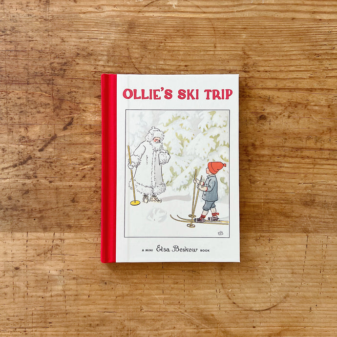 Front cover of Elsa Beskow's mini hardcover book, Ollie's Ski Trip. The book is bound with red fabric. The illustration shows a boy in a red cap talking to a snow white and frost covered Jack Frost. 