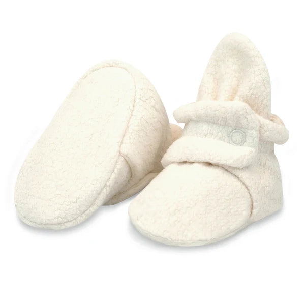Heather Cream fleece baby booties, with one tilted to show the plain fabric sole used in sizes 3M and 6M.
