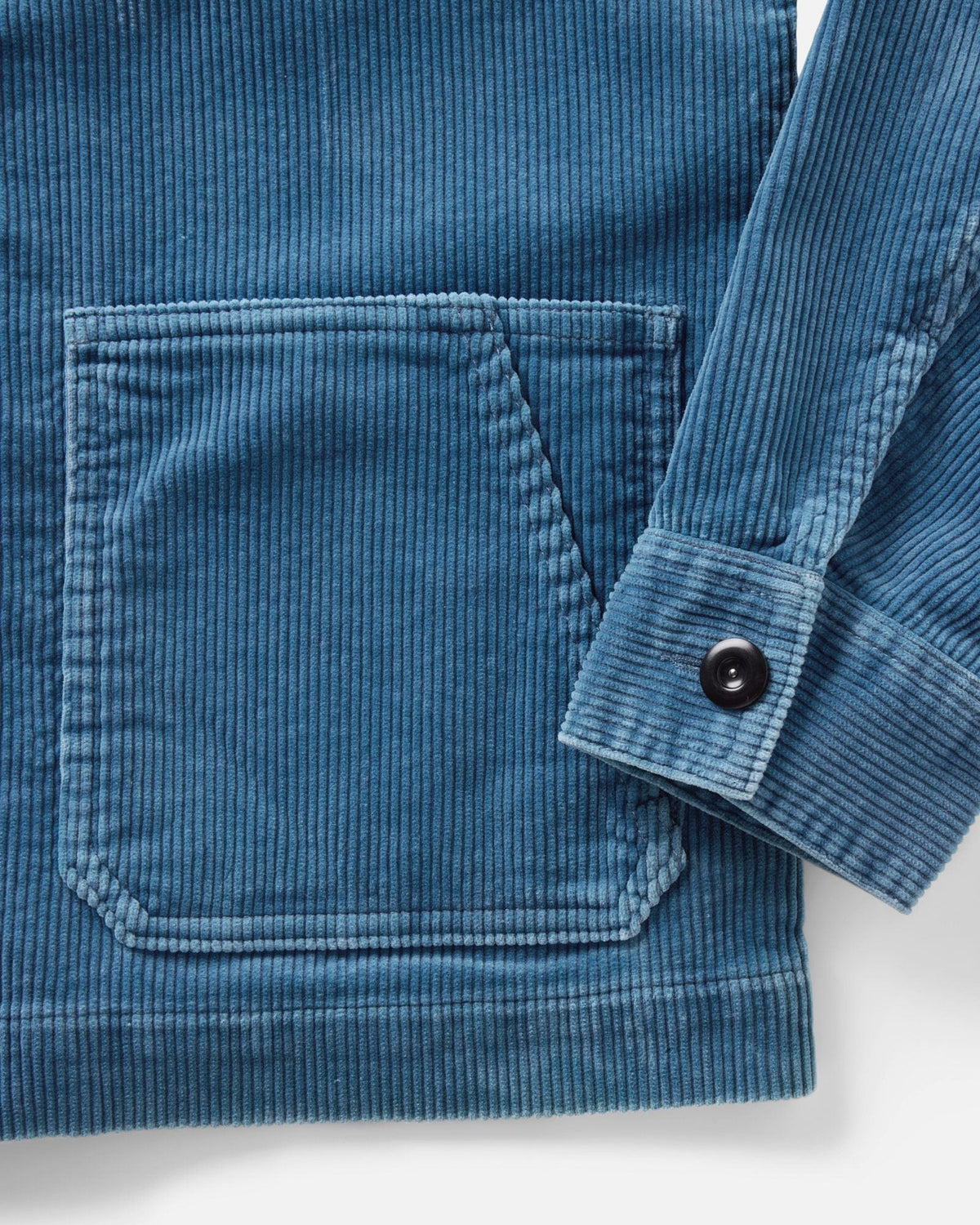 Close-up of the Ojai Jacket in Washed Indigo Corduroy, showing the ribbed texture, dual-entry lower patch pocket, and buttoned cuff.

