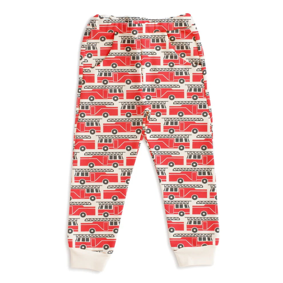 A pair of children's jogger pants featuring an all-over red fire truck pattern on a white background, with white ribbed cuffs at the ankles.