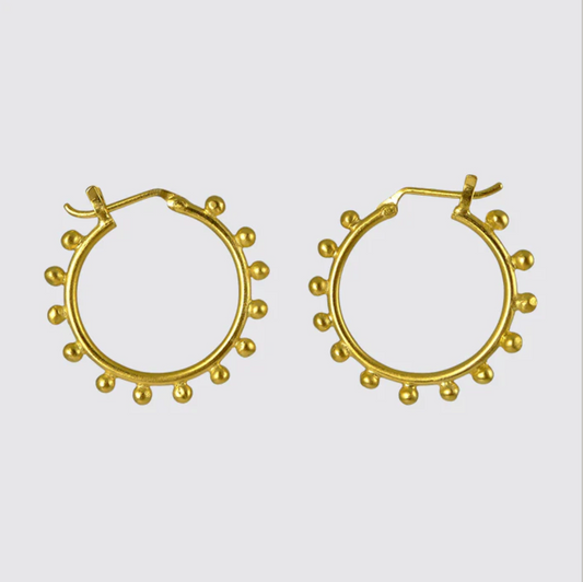 Gold hoop earrings with small spherical embellishments on a light gray background