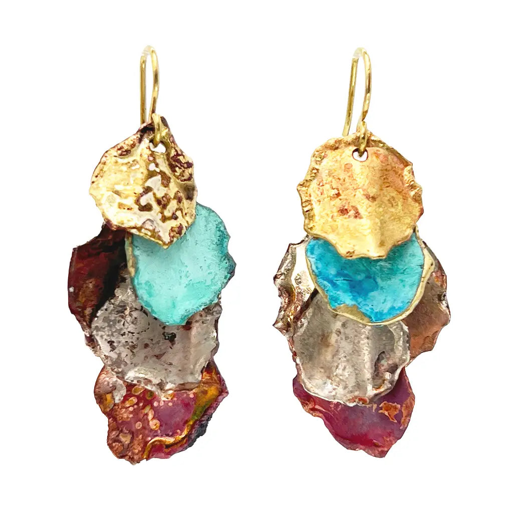 Pair of Sibilia Small Cometa Earrings in Mixed Canyon Patina, featuring three stacked irregular organic-shaped treated brass fragments in gold, turquoise, and red-brown mixed canyon patina, hanging from gold wire hooks, on a white background