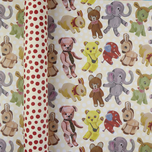  Plushies wrapping paper by Nathalie Lété shown rolled and flat, displaying vintage-style illustrated plush animals including teddy bears, elephants, rabbits, and donkeys on a cream background, with the red polka dot reverse visible on the rolled tube
