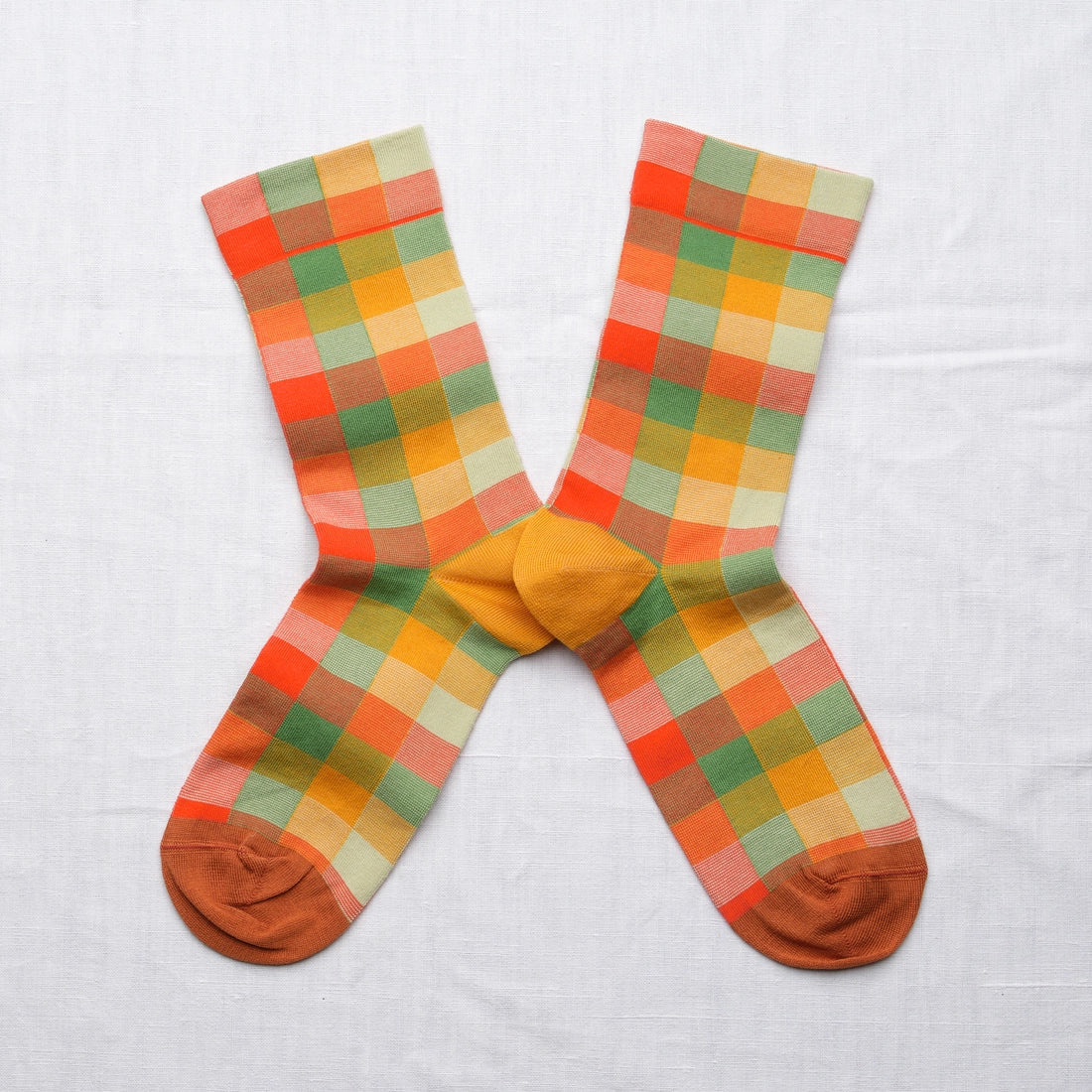 Bonne Maison Multicolor Plaid Socks, flat lay pair showing the multicolor plaid pattern in orange, red, green, yellow, and cream with mustard heel and toe

