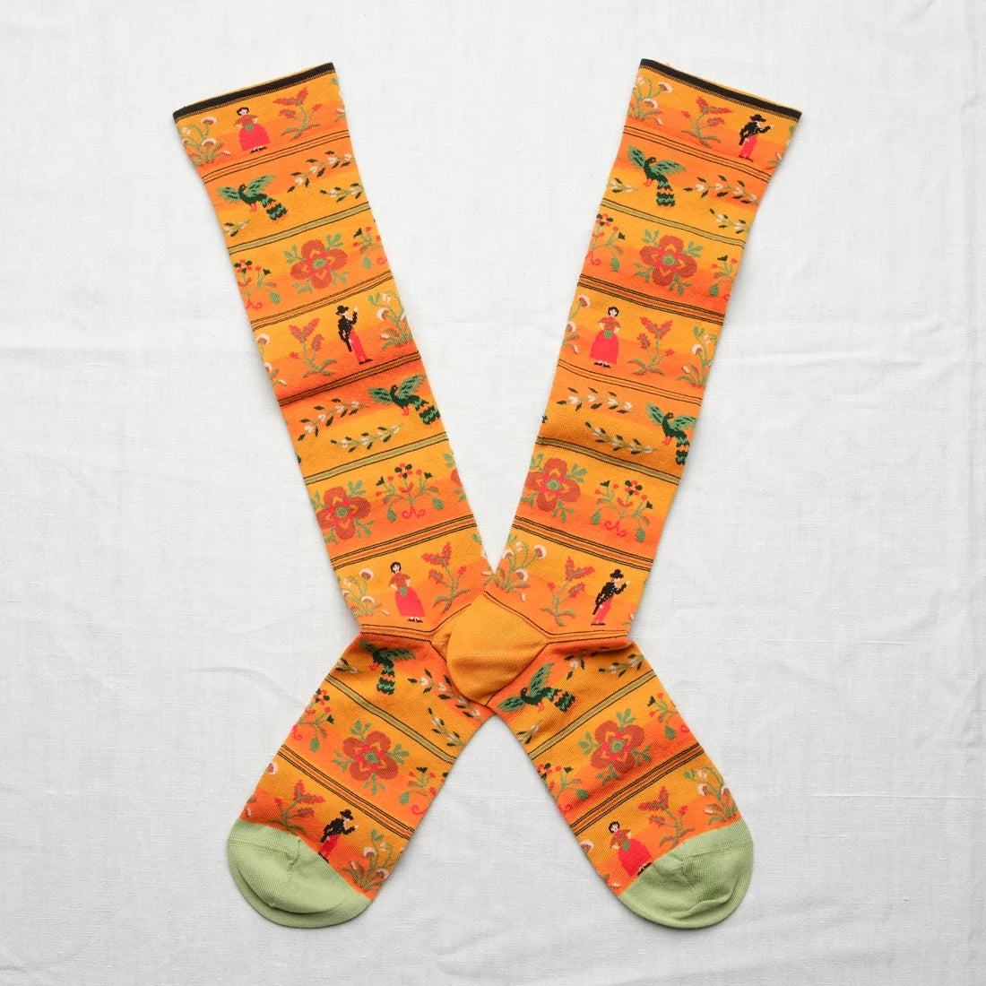 Bonne Maison Amber Character Knee High Socks, flat lay pair showing the amber ground with folk-style character and floral stripe bands and sage heel and toe
